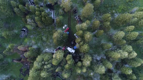 Aerial view over campsite as people sit around campfire alt