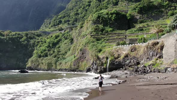Woman walking on Seixal black sand beach, Madeira, Portugal alt
