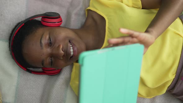 High Angle View Happy Woman in Headphones Messaging Online on Tablet Smiling Lying on Blanket in alt