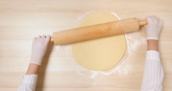 4K - Rolling pin rolls out the Dough. Top view alt