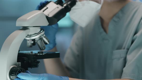 Female Lab Scientist in Protective Uniform Using Microscope alt