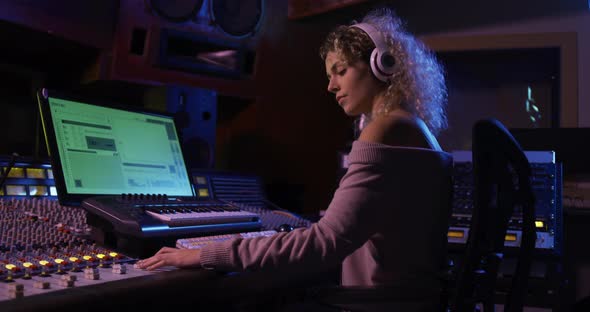 Female sound engineer working at a mixing desk alt