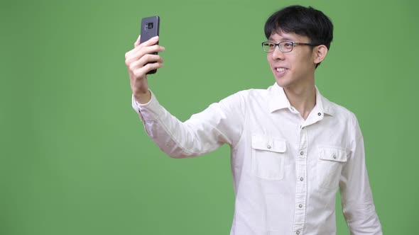 Happy Young Asian Businessman Taking Selfie with Phone alt