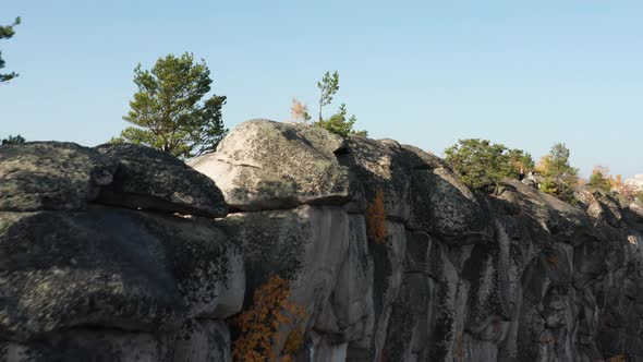 Aerial View of a Cliff Surrounded By a Colorful Autumn Forest at Sunset alt