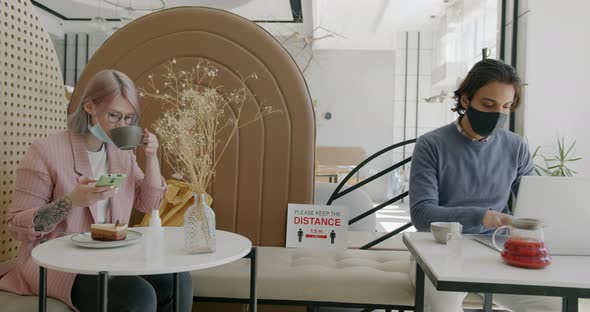 Business People Wearing Face Masks Working in Cafe Using Devices Observing Social Distancing alt