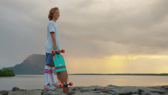 Happy Teenager Stylish Skater Boy Holding His Skateboard Outdoors alt