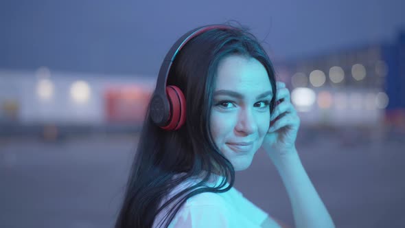 Close-up of Young Positive Woman in Blue Neon Lights Turning To Camera and Smiling. Portrait of alt