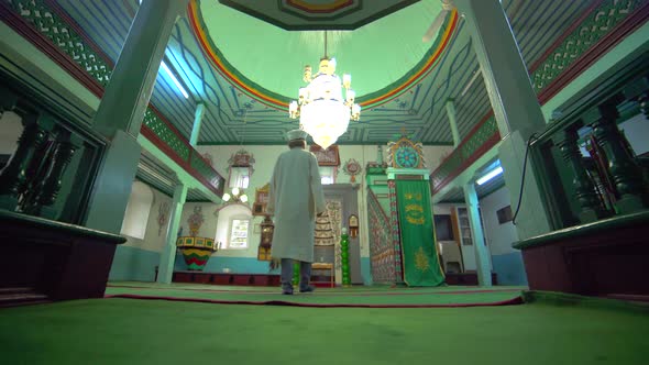 Muslim Mosque Teacher is reading the Quran in Small Historic Wooden Masjid