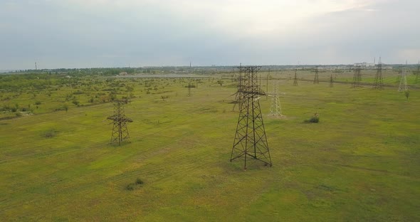 Large Pylons Of Power Lines On A Green Field, In The Afternoon