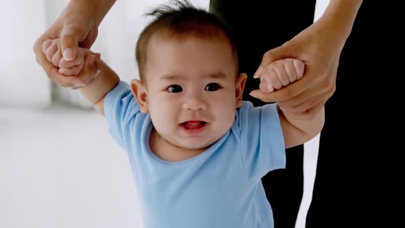 Happy little baby learning to walk with mother support and care. alt