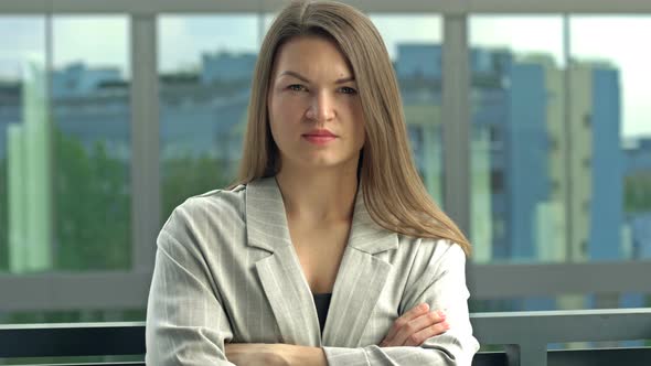 Portrait of a Young Woman in a Business Suit Against the Backdrop of an Office Window