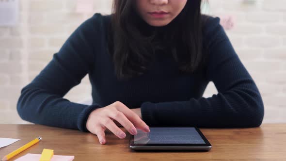 Female college student concentrating on reading e-book from tablet computer at the table