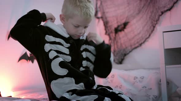 Halloween Kids Happy Boy Puts on Halloween Skeleton Costume at Home alt