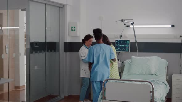 Afro American Nurse with Doctor Helping Patient to Stand Up From Bed alt