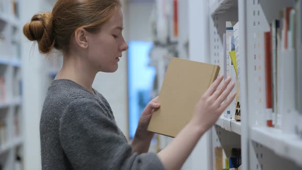 Redhead Woman Searching and Reading Book in Library alt