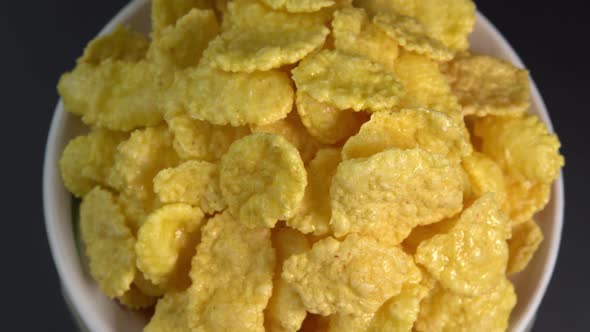 Crispy corn flakes rotating in bowl close up, dry healthy breakfast. Honey cornflakes for healthy alt