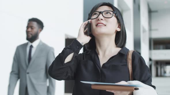 Asian Woman with Boarding Pass Chatting on Mobile Phone in Departure Lounge alt