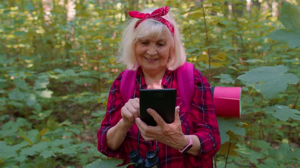 Active Elderly Senior Grandmother Adventurer Exploring Forest Trees Plants with Her Digital Tablet alt