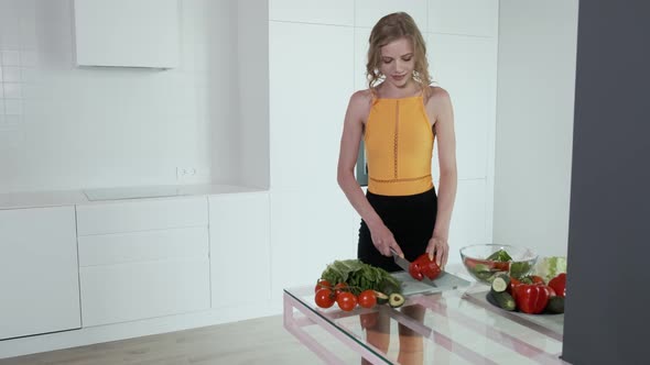 Young Woman Slicing Red Pepper For Vegetable Salad.