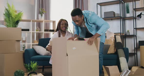 Couple Having Fun Together with Their Two Cute Small Daughters which Hiding in Cardboard Packing alt
