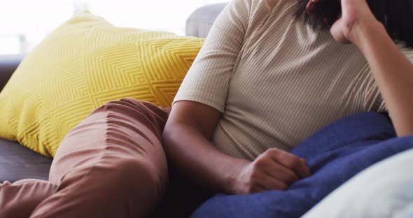 Close up of gender fluid male looking out of window while sitting on the couch at home alt
