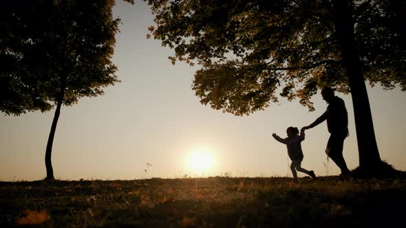 Against the Background of the Bright Orange Sunset Sky the Silhouette of the Father and Daughter alt