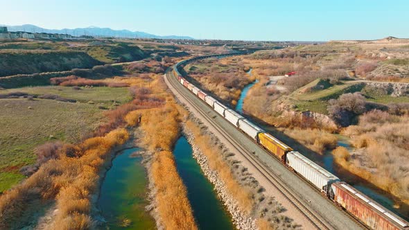 AERIAL - Train on railroad tracks close to Bluffdale, Utah, forward lowering shot alt