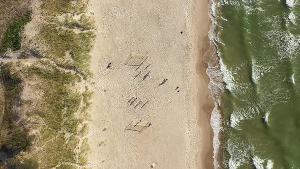 AERIAL: Top View Shot of Football Players Shadows on a Sandy Beach