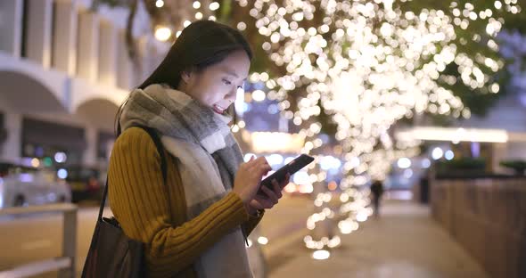 Woman working on cellphone in the city at night alt