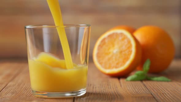Slow Motion Shot of Fresh Orange Juice Being Poured in a Glass. alt