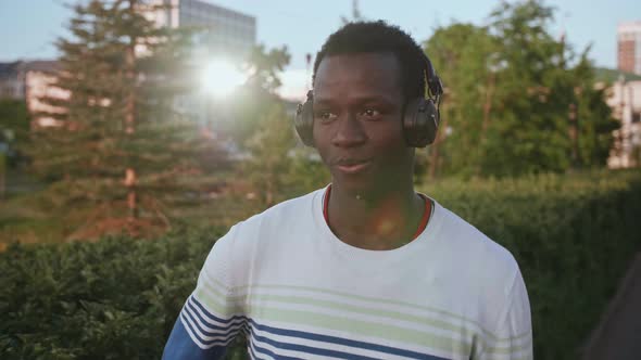 Black Young Man Listens to Music with Headphones