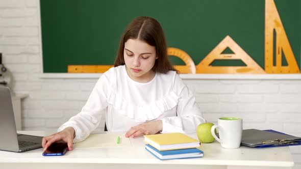 Serious Kid Doing Classwork Using Mobile Phone in Classroom Smartphone Learning alt