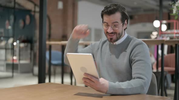 Young Man Celebrating Success on Tablet in Office alt
