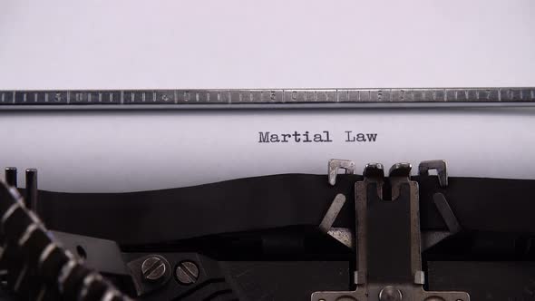Typing phrase "Martial Law" on retro typewriter. alt