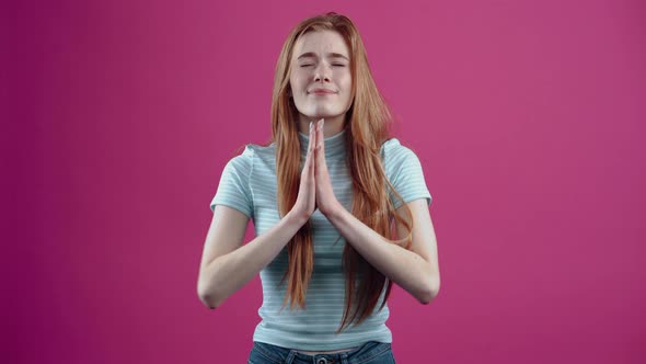 The Redhaired Young Woman Prays Hopefully Crossing Her Fingers That Her Wish Will Come True in a alt