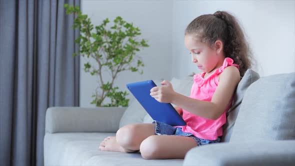 Curious Cute Kid Little Girl Using Digital Tablet Technology Device Included in Studies Sitting on alt