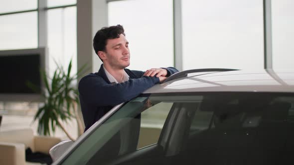 Auto Business Happy Man Rejoices in Buying a New Car From a Vehicle Dealership Smiles and Shows