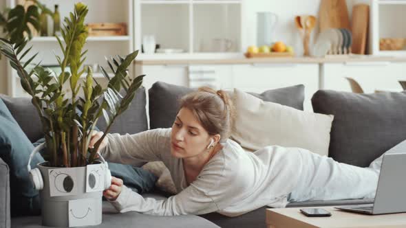 Cheerful Woman Sitting on Couch and Web Calling on Smartphone at Home alt