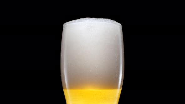 Light Beer is Pouring Into Glass on a Black Background