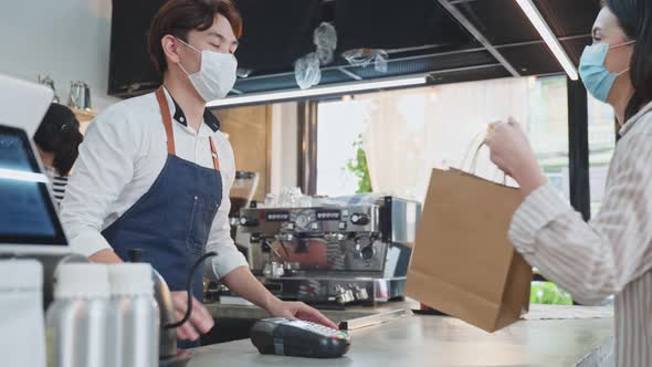 Asian woman customer make a quick contactless payment use credit card in cafe during Covid19. alt