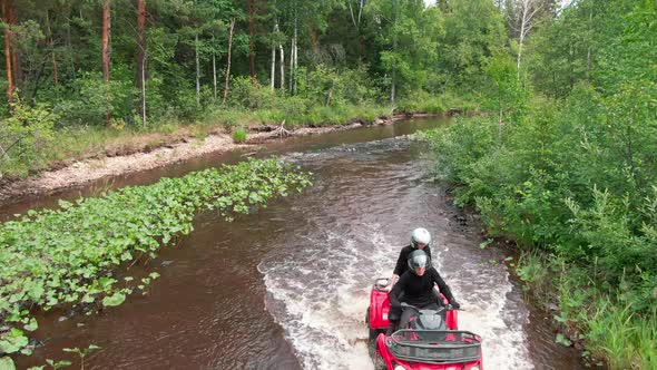 Aerial Shot of People Driving ATV through River alt