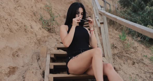 Brunette Woman Wearing Sunglasses at the Stairs Near Sea alt