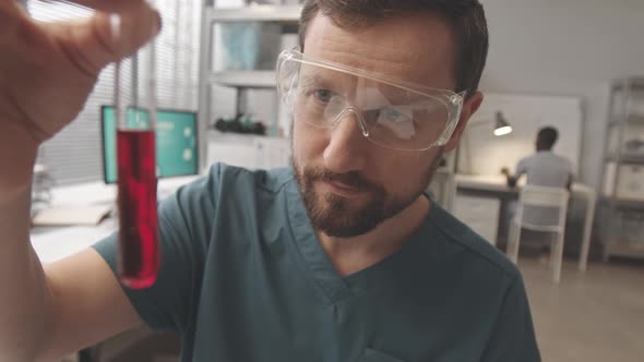 POV of Chemists Examining Liquid Substance in Test Tube in Lab alt