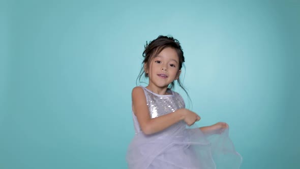 Beautiful Little Child Girl in Silver Dress Dancing on Blue Background