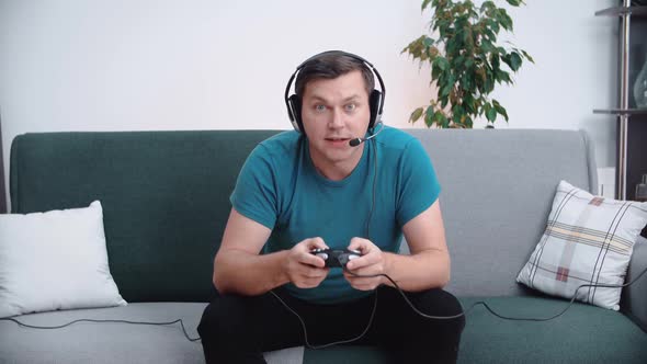 A Man Enthusiastically Plays Video Games with a Gamepad and Headset
