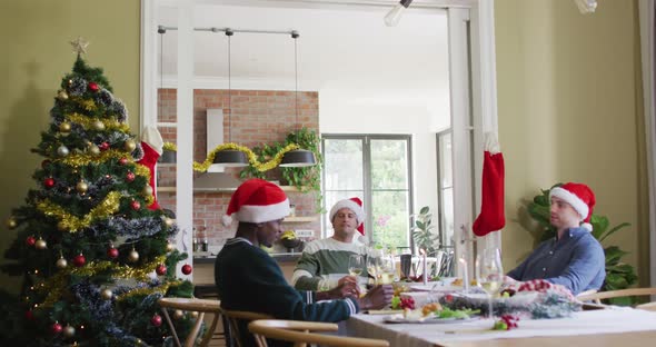 Happy group of diverse friends in santa hats celebrating meal at christmas time alt