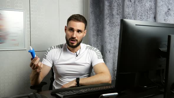 Young Bearded Business Coach Giving Online Lesson About Vision Correction Drops While Working at alt