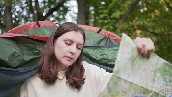 A Female Tourist Exploring the Map While Sitting in a Tent
