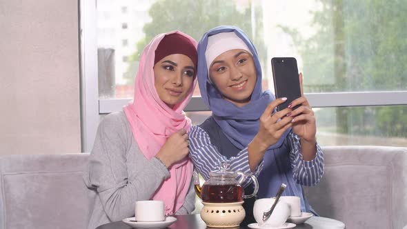 Beautiful Young Muslim Girls Do Selfie on a Smartphone alt