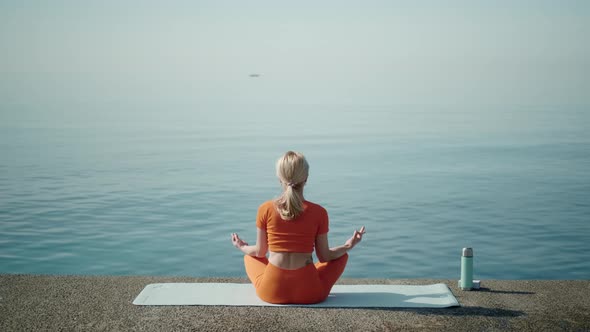 A Woman Sits in a Lotus Position Alone on the Seashore